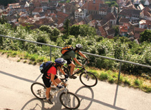 Two cyclists ride on a path above the old town
