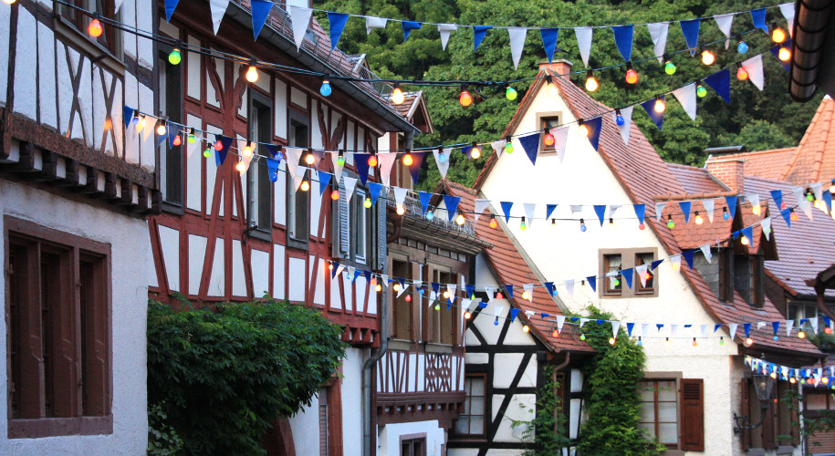 half-timbered houses with blue corners stretched across the road and colourful lights