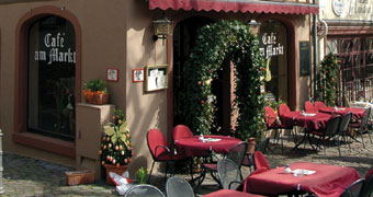 Tische und Stühle vor dem Café am Markt mit roten Tischdecken und Stuhlkissen