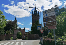 Road signs in front of the silhouette of the Berckheimer Castle with a bright blue sky