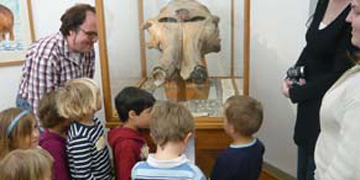 Kids at a guided tour facing the mammoth skull at a showcase